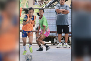 TOP STRIKER. Queency Love Canaman of Bulua National High School (left) escapes past Lumbia National High School defender Jamz Navarro Esteban as Bulua coach Jun Actub watches in their tune-up match at the Bulua NHS gym in preparation for the Palarong Pambansa. (Photo by Kjay Francisco Edorot)
