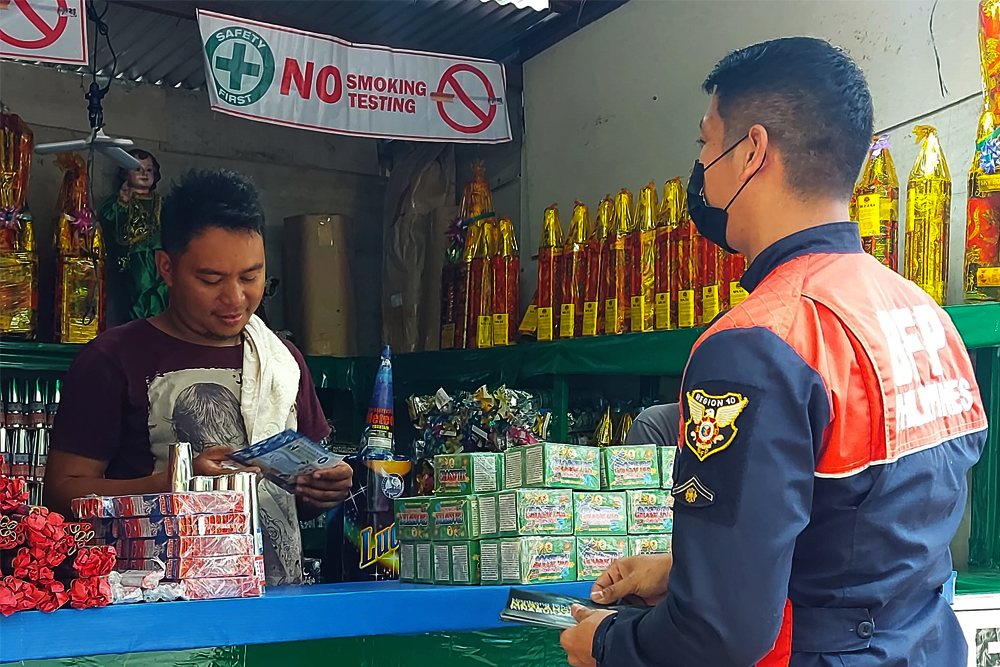 A vendor selling various types of firecrackers and fireworks receives a pamphlet from a BFP personnel in Cagayan de Oro. (Photo courtesy of Menzie Montes)