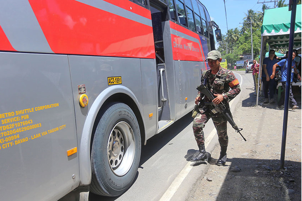 A member of Task Force Davao prepares to board a passenger bus for inspection. (Manman Dejeto | MindaNews)