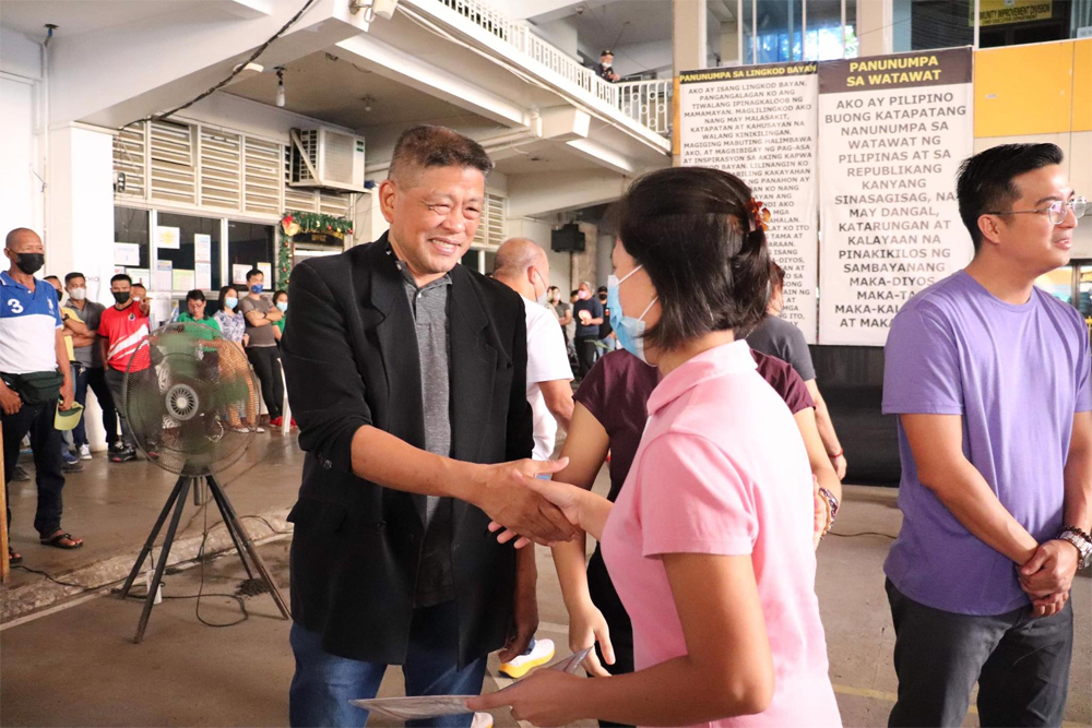 City Administrator Roy Hilario Raagas (left, wearing black coat), shown here congratulating a housing beneficiary in Tuesday morning’s flag-raising program, said all City Hall departments will review the performances of their respective casuals and job order workers to determine if they will be renewed or not. (Jay Arancon | CIO)